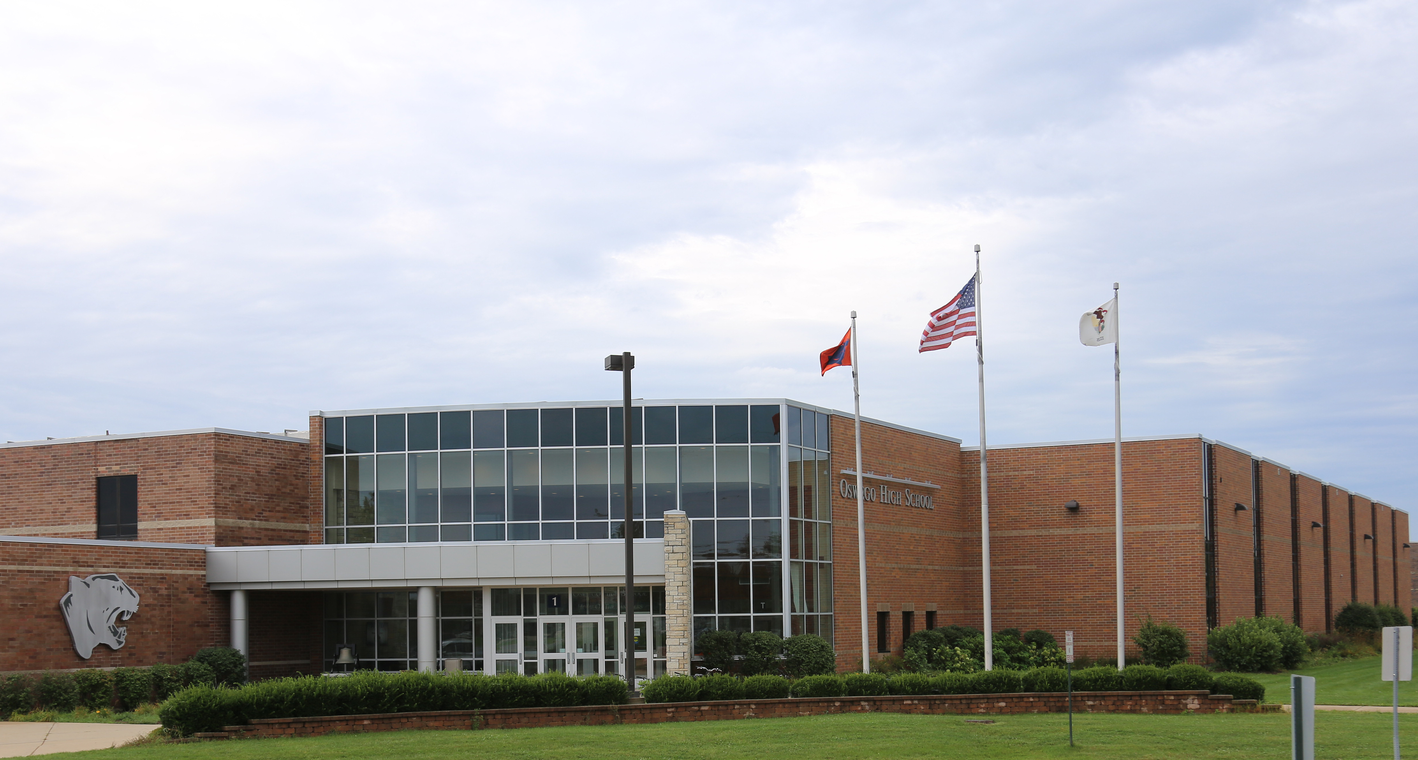 Oswego High School visitors entrance with panthers and US flag outside. 